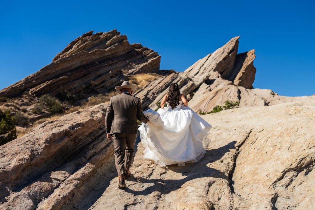 Couple exploring dramatic sandstone rocks on their wedding day